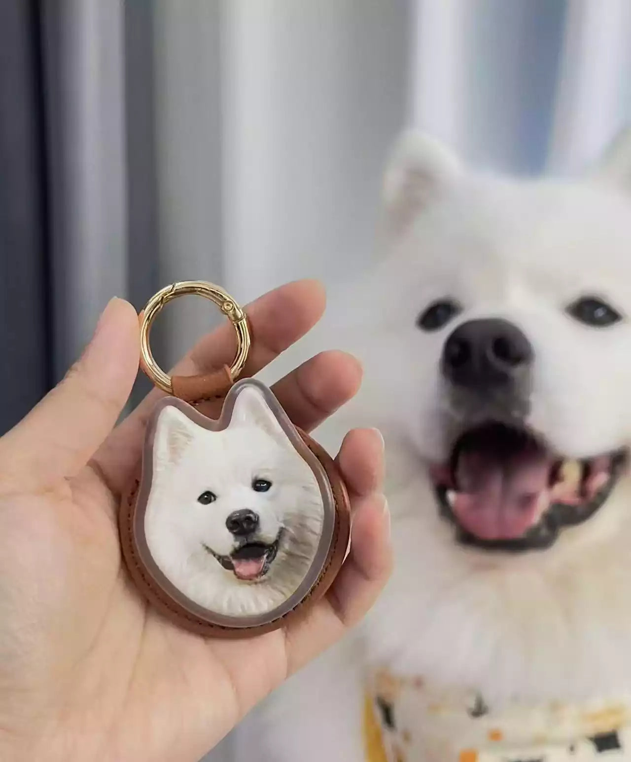 Hand holding a custom acrylic dog photo keychain with the smiling white dog in the background.