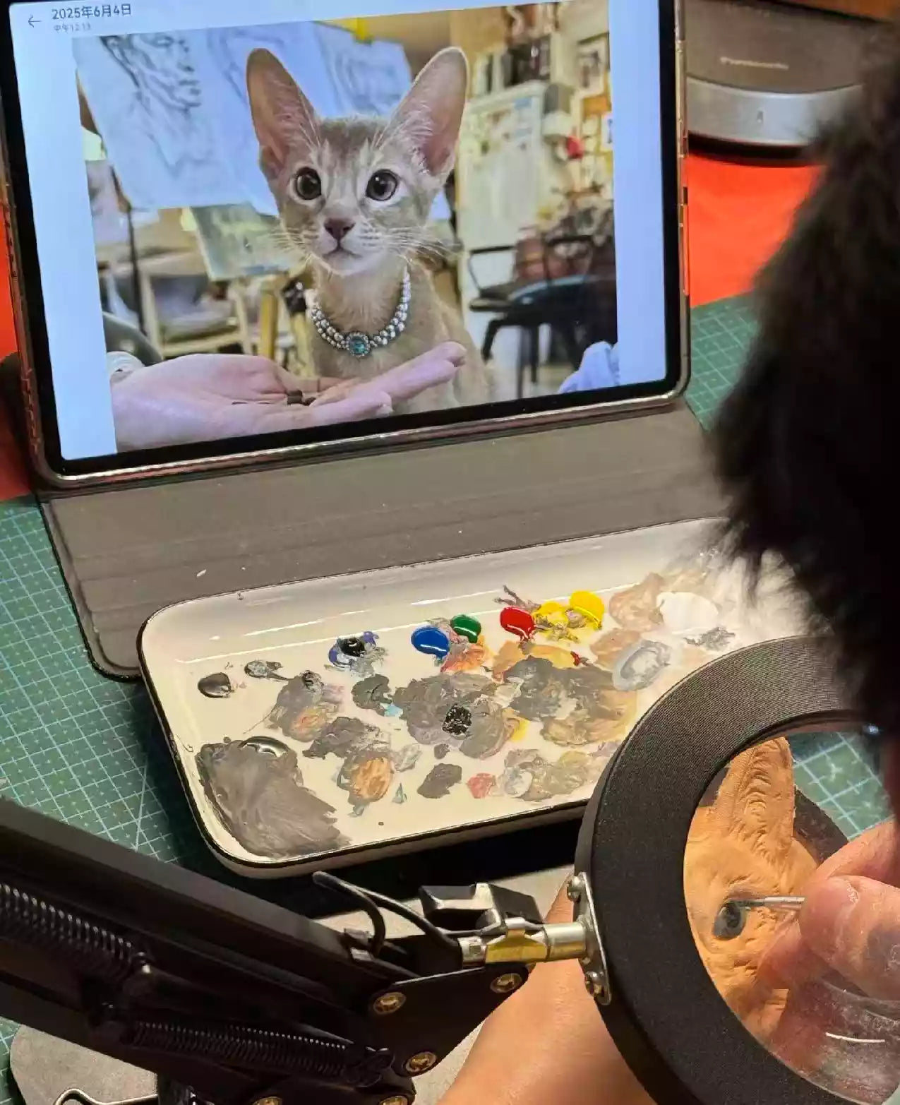 Work-in-progress view of a custom leather pet portrait keychain being made, with the reference photo on a screen.