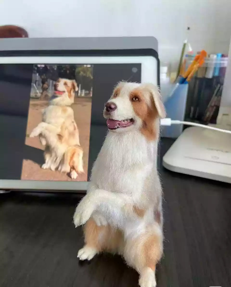Needle-felted dog figurine displayed in front of a screen showing the reference photo.