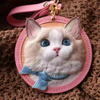 Custom leather cat portrait bag charm with pink strap and round stitched leather frame.

