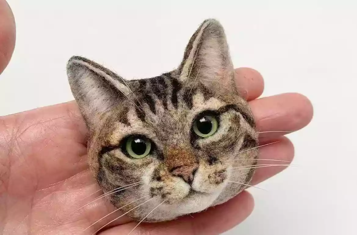 Hand holding a custom 3D cat head replica with realistic tabby markings